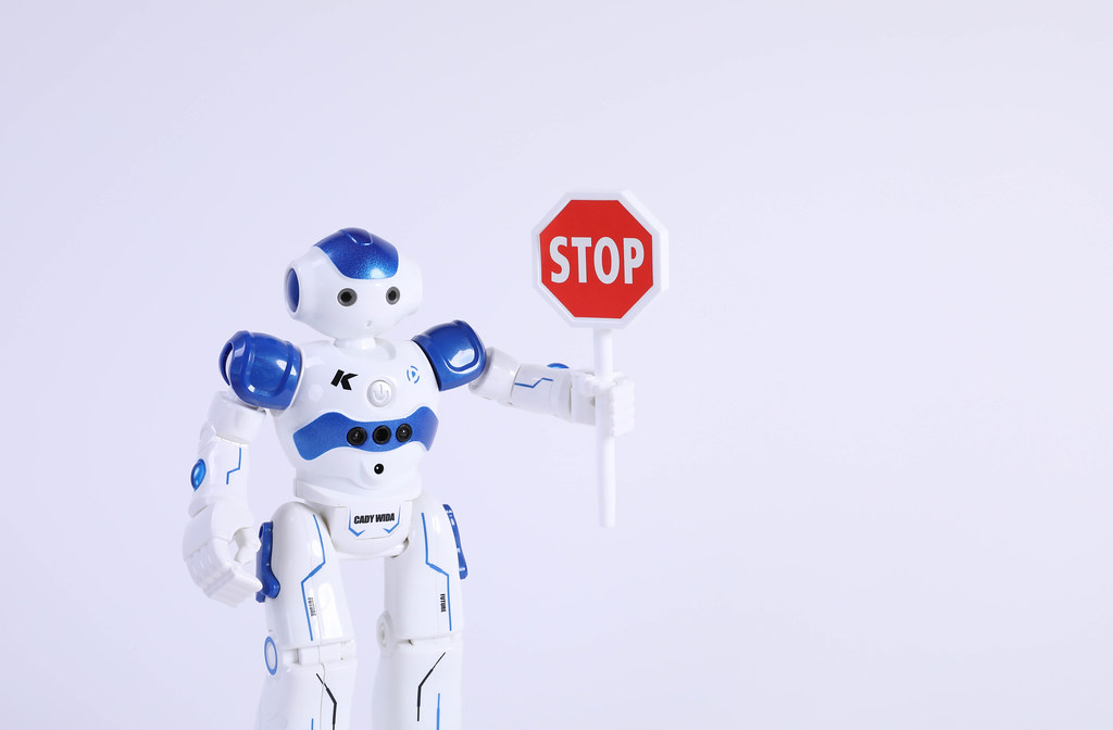 Robot holding Stop sign on white background