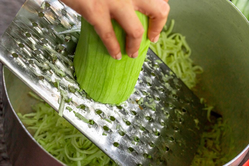 Rubbing zucchini on a metal grater
