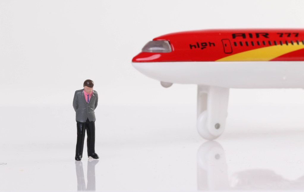 Sad businessman standing near airplane