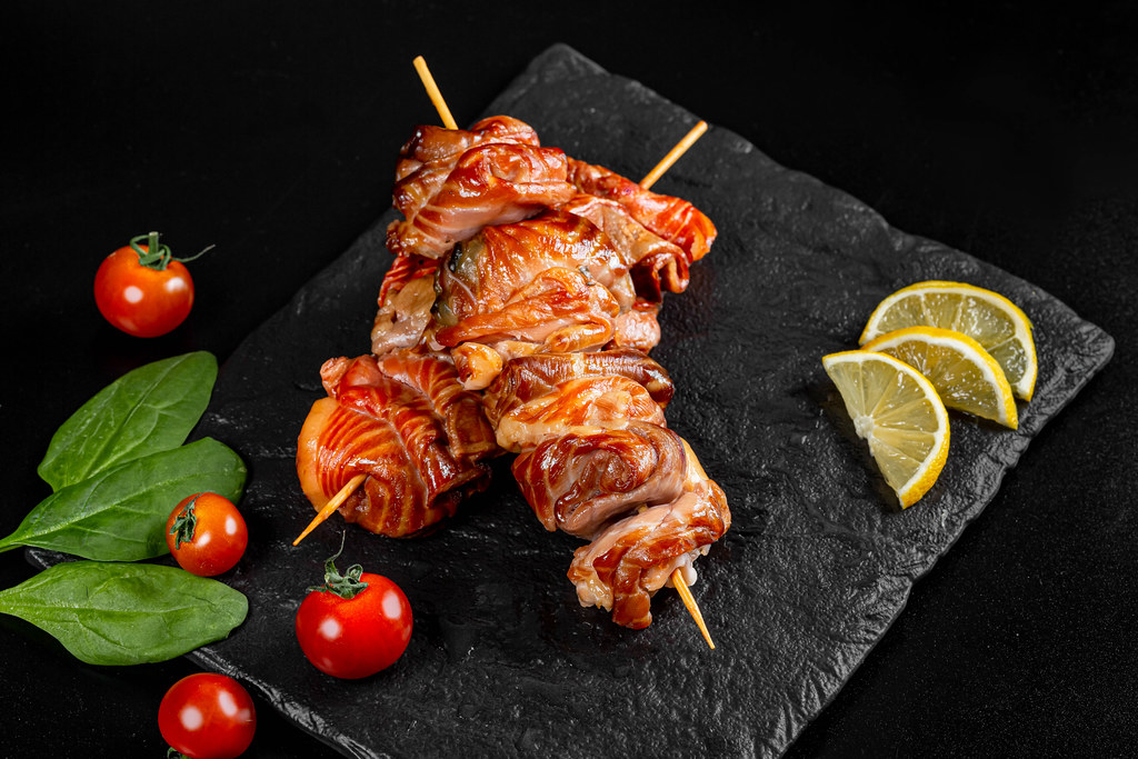 Salmon fillet on wooden sticks with lemon slices and cherry tomatoes on a dark background