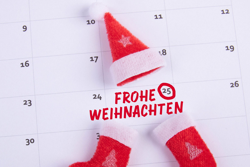 Santas Claus hat and socks with Frohe Weihnachten text on the calendar