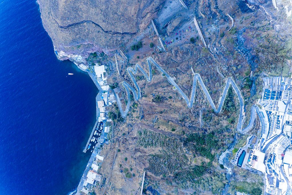 Santorini from above: the Aegean sea, the old port of Firá, the zigzag pathway climbing up the steep cliffs