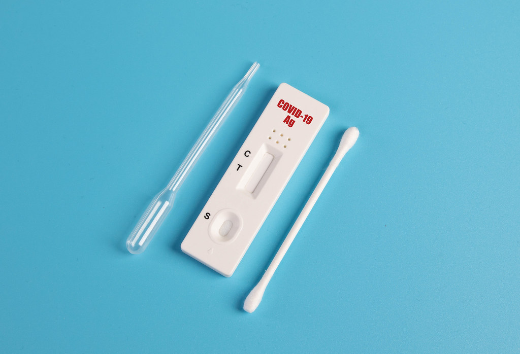 SARS-CoV-2 Rapid Antigen Test isolated on blue background with nasal swab stick