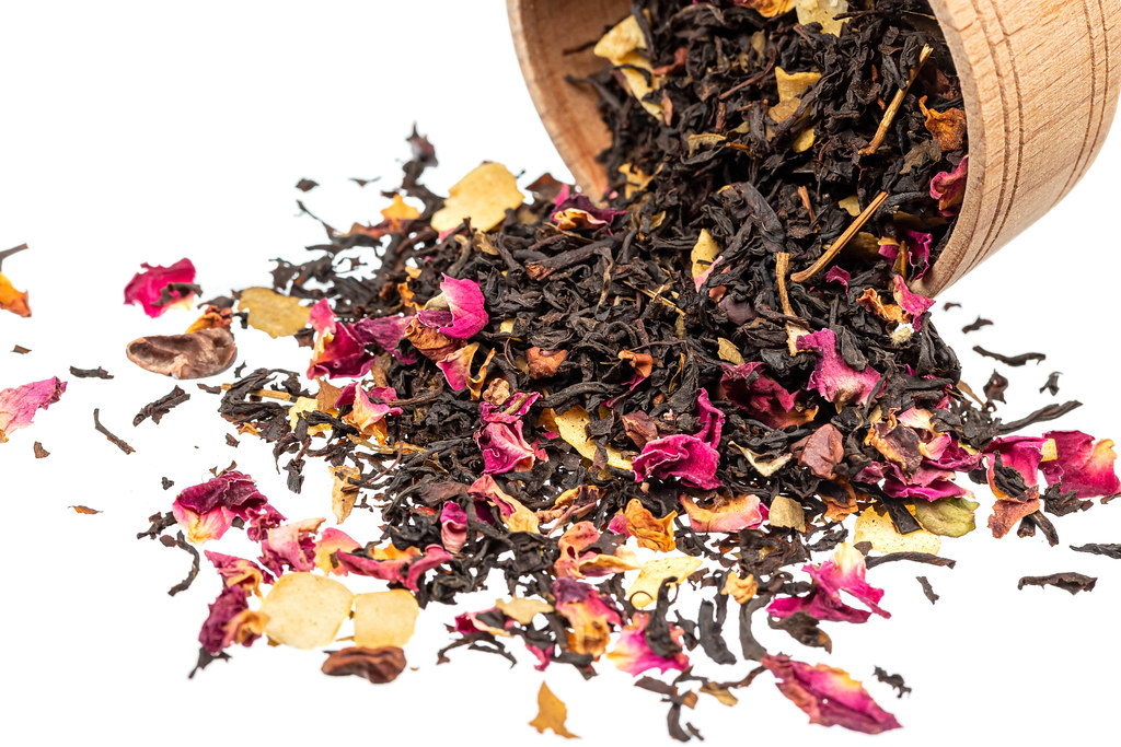 Scattered black tea with petals on a white background
