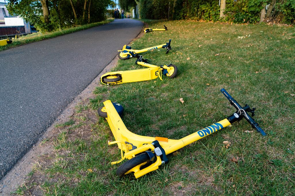 Scooters from Wind sharing are laying dropped on the side of the road