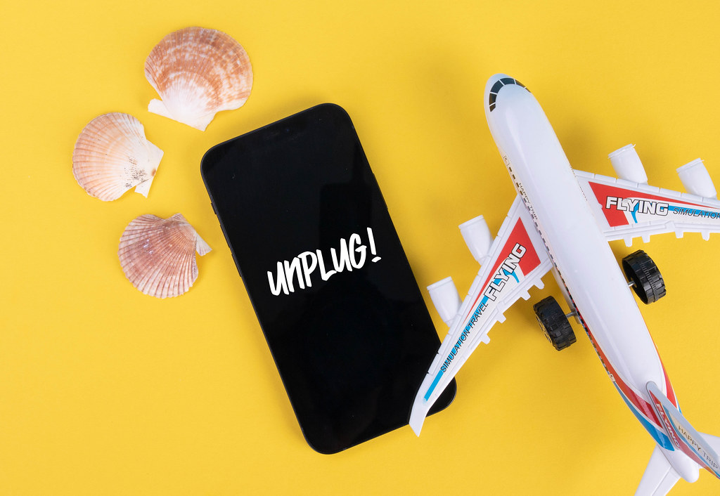 Sea shells, airplane and smartphone with Unplug text