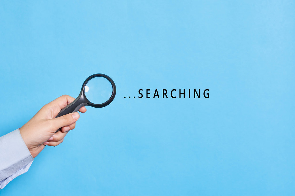 Searching. Hand of detective holding a magnifying glass