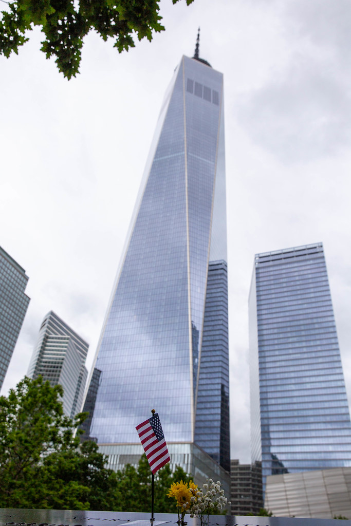 September 9 Memorial with american flag and flowers in front of the tallest building in the USA, One World Trace Center in Lower Manhatten