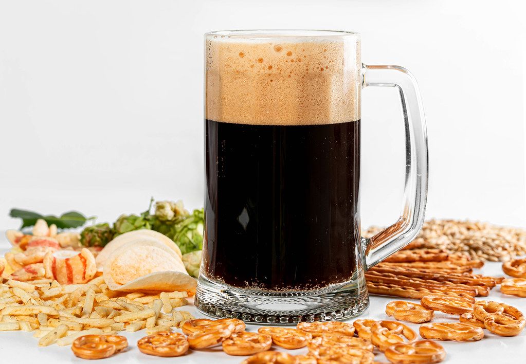 Set of different snacks on a white background with a glass of fresh beer