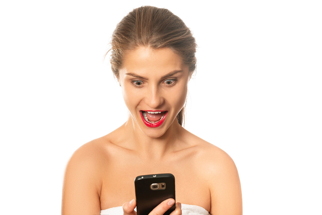 Shocked surprised girl looking at mobile phone with open mouth