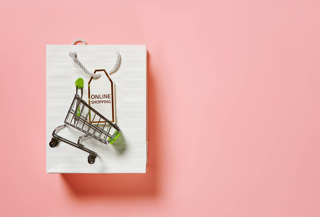 Shopping bag and shopping cart on pink background