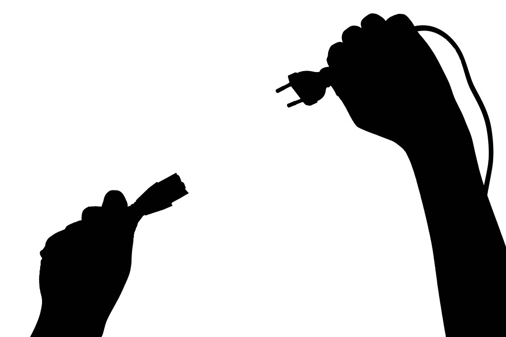 Silhouette of hands trying to connect european plug isolated over white background