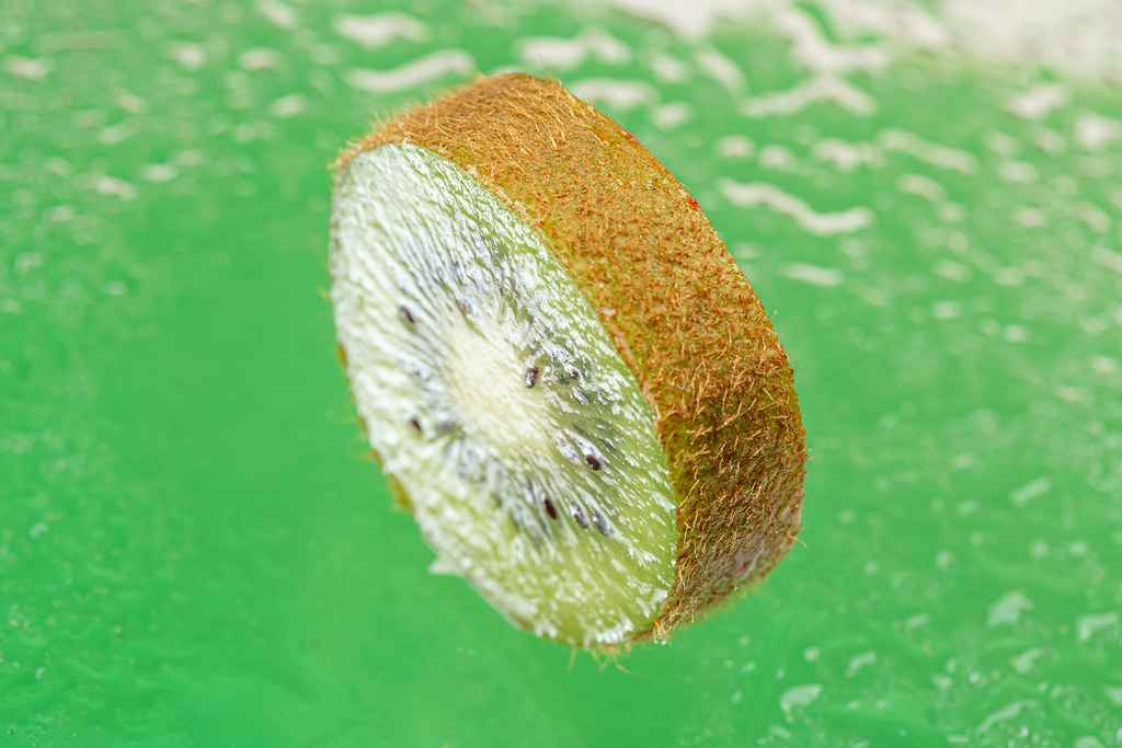 Slice of ripe kiwi on a green background