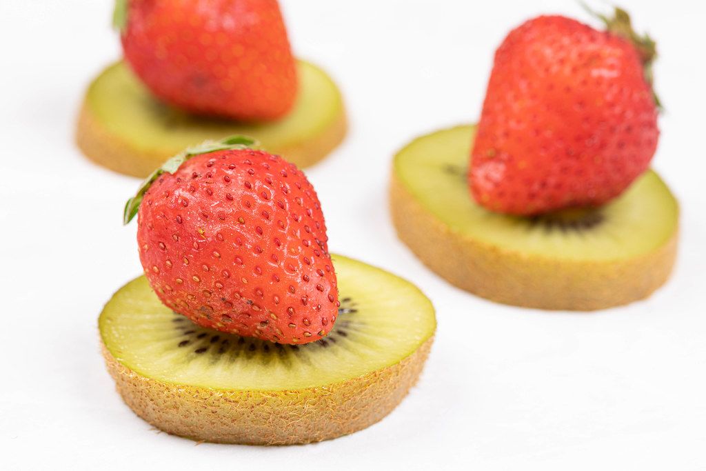Sliced Kiwi and Strawberries arranged on the white table