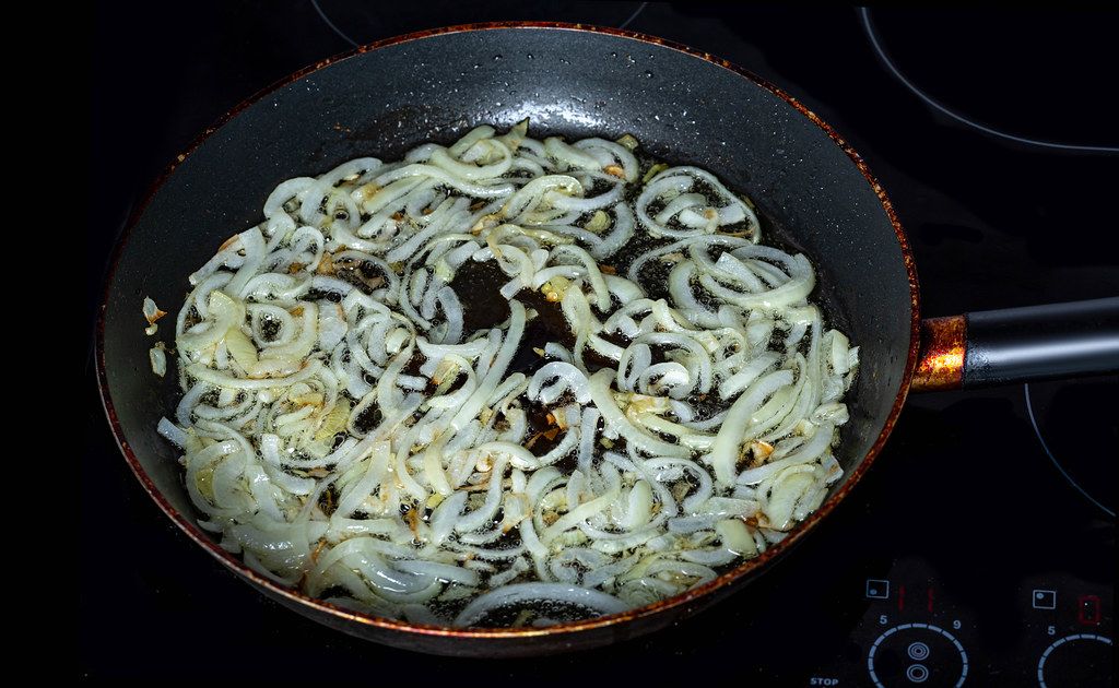 Sliced onions fried in a frying pan