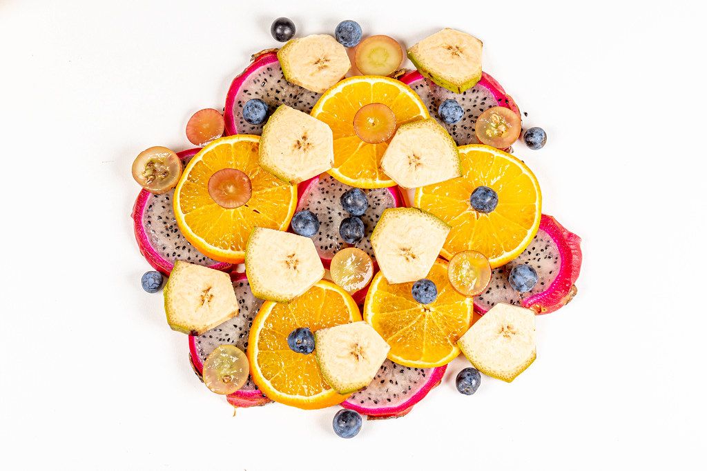 Sliced pitahaya, plantain, tangerine, grapes and blackthorn berries, top view