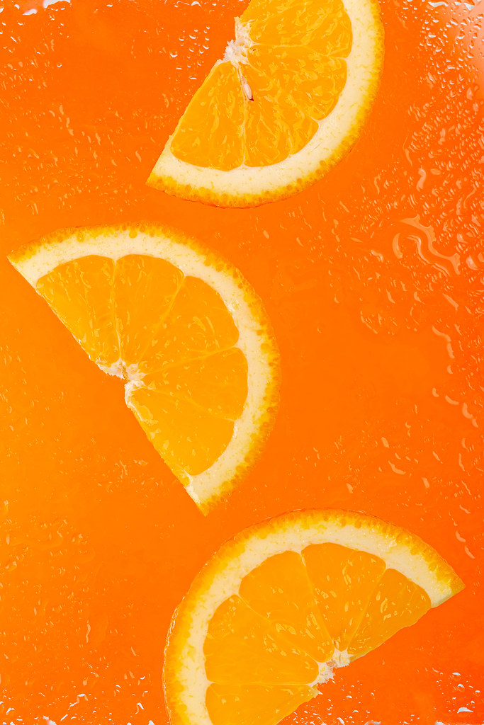Slices of ripe orange on an orange background with water drops