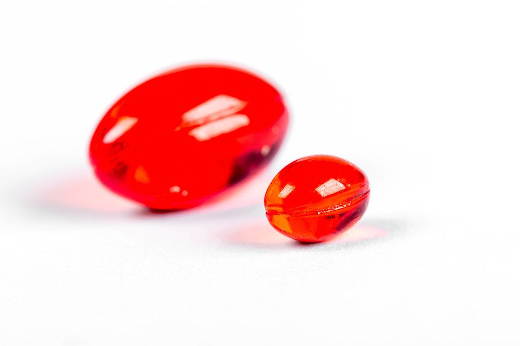 Small and large red capsules on white