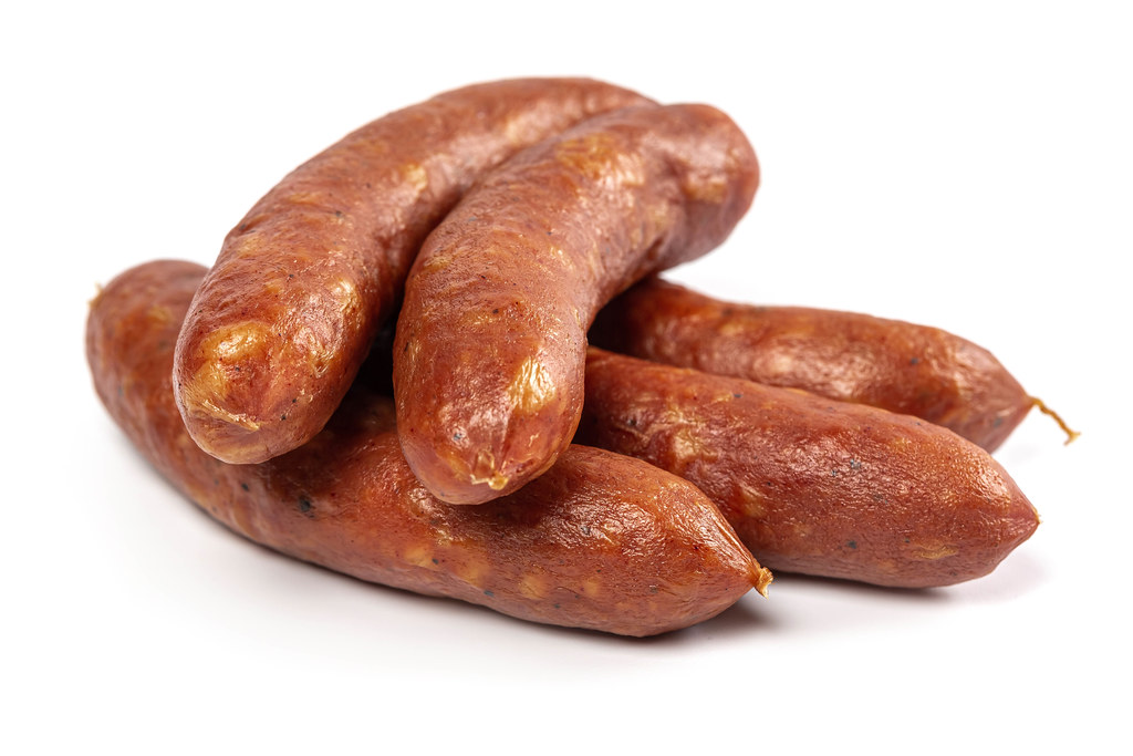 Small smoked sausages on white background