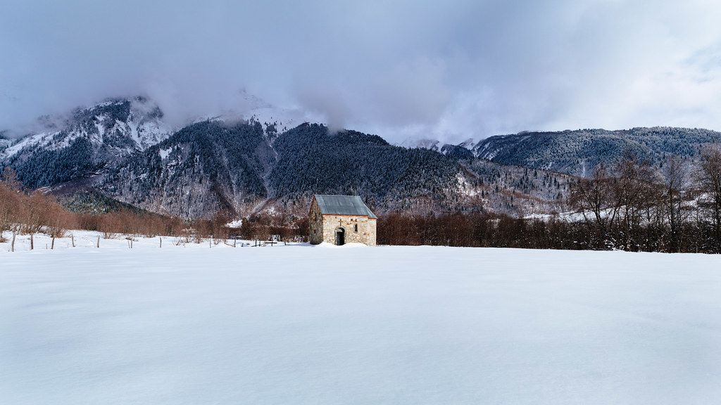 Small stone church in the middle of nowhere surrounded by snow and mountains