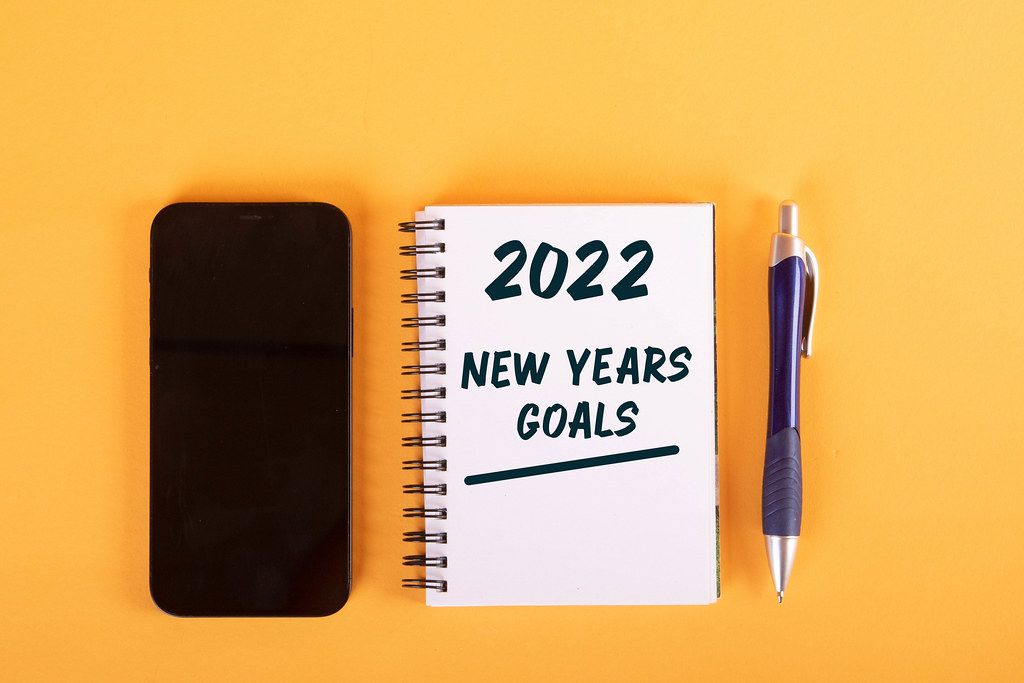 Smartphone and notebook with 2022 New Years Goals text on yellow background