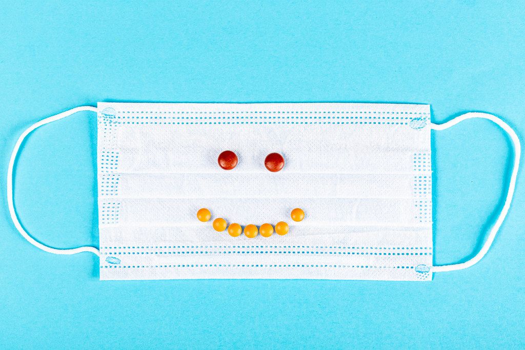 Smiley face from pills on a medical mask, top view