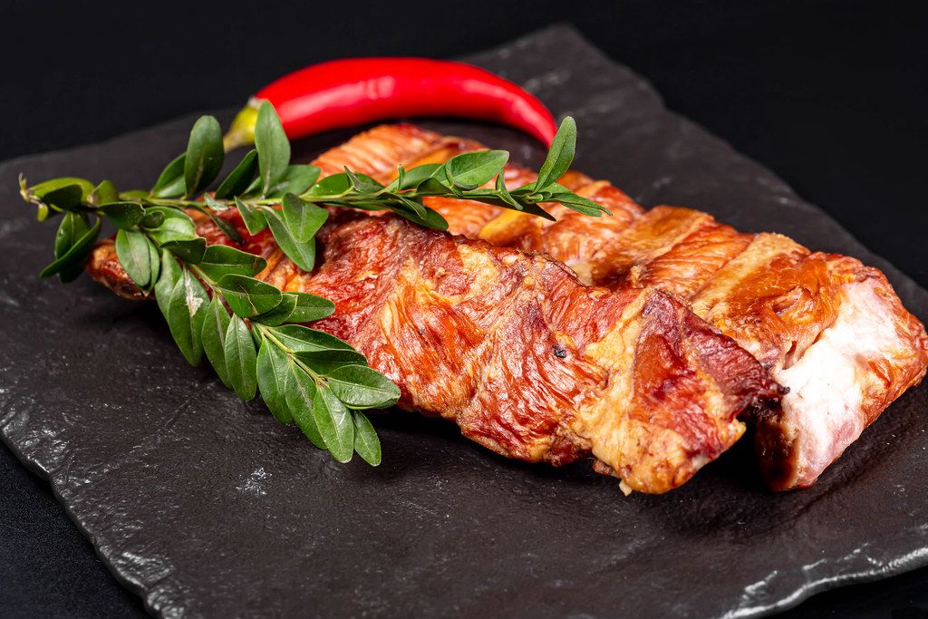 Smoked ribs with red chili on black stone background