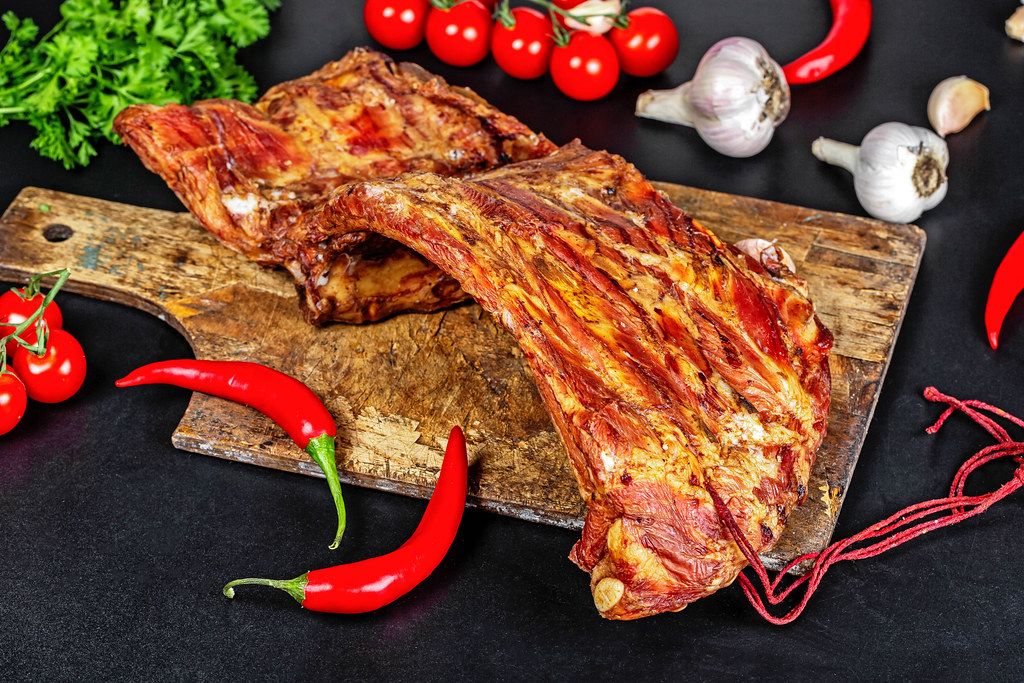 Smoked ribs with spices and vegetables on a black background