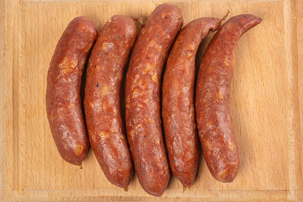 Smoked sausages on wooden kitchen board, top view