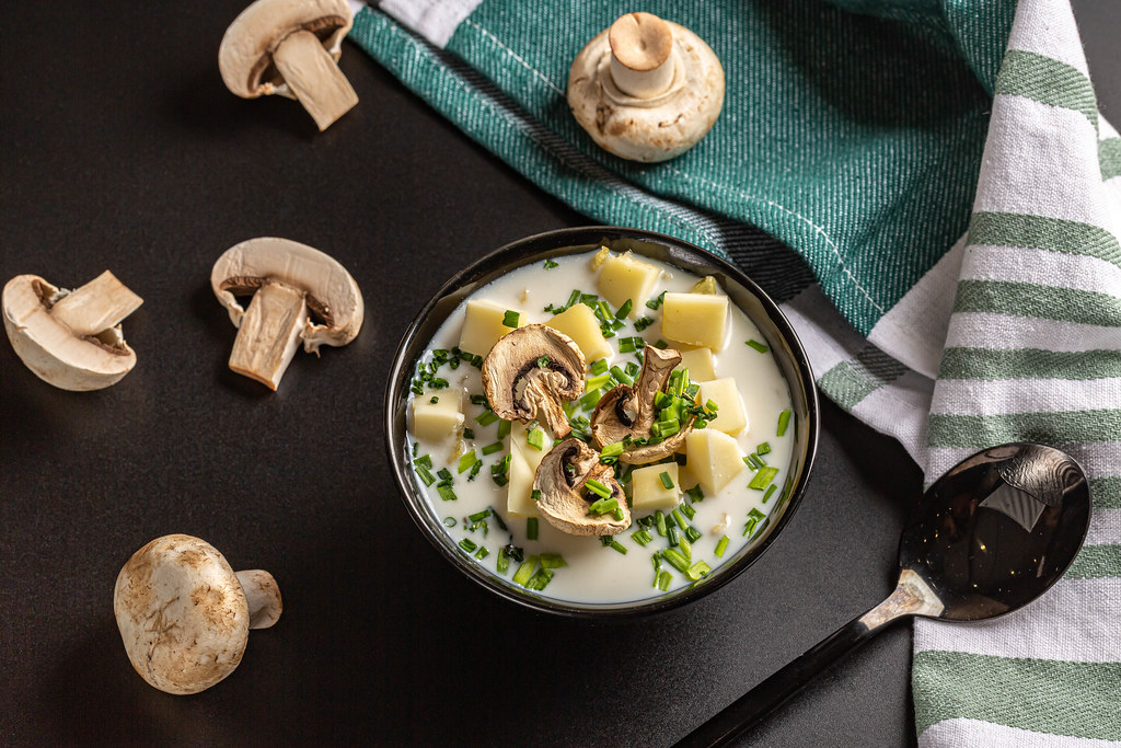 Soup with dried champignons, green onions and cheese on a dark background