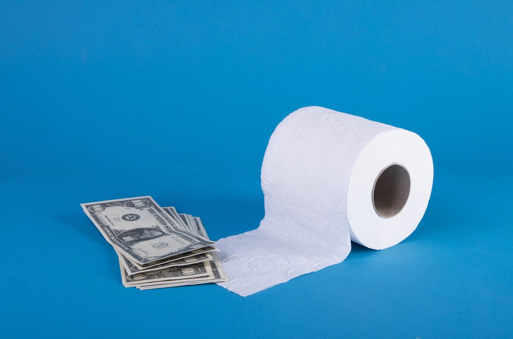 Stack on money with toilet paper on blue background