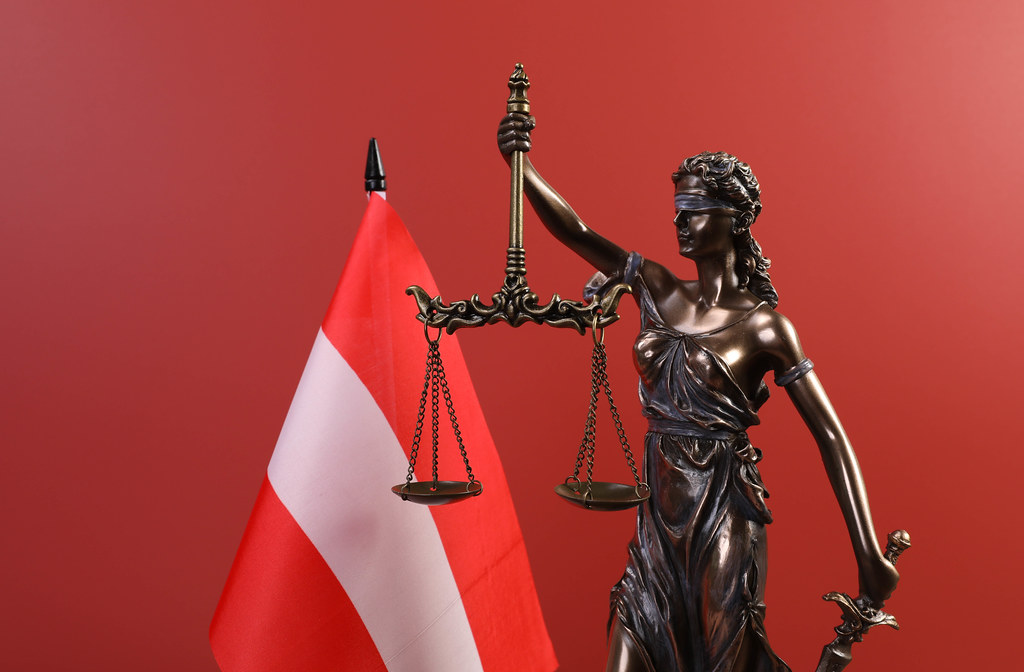 Statue of Lady Justice and flag of Austria on red background