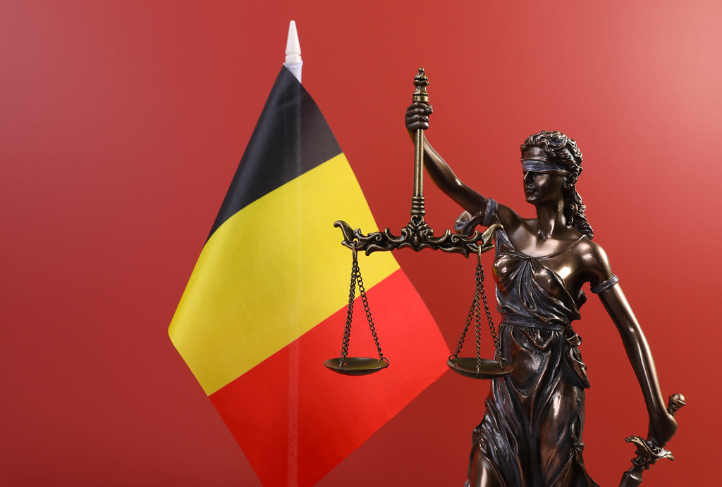 Statue of Lady Justice and flag of Belgium on red background
