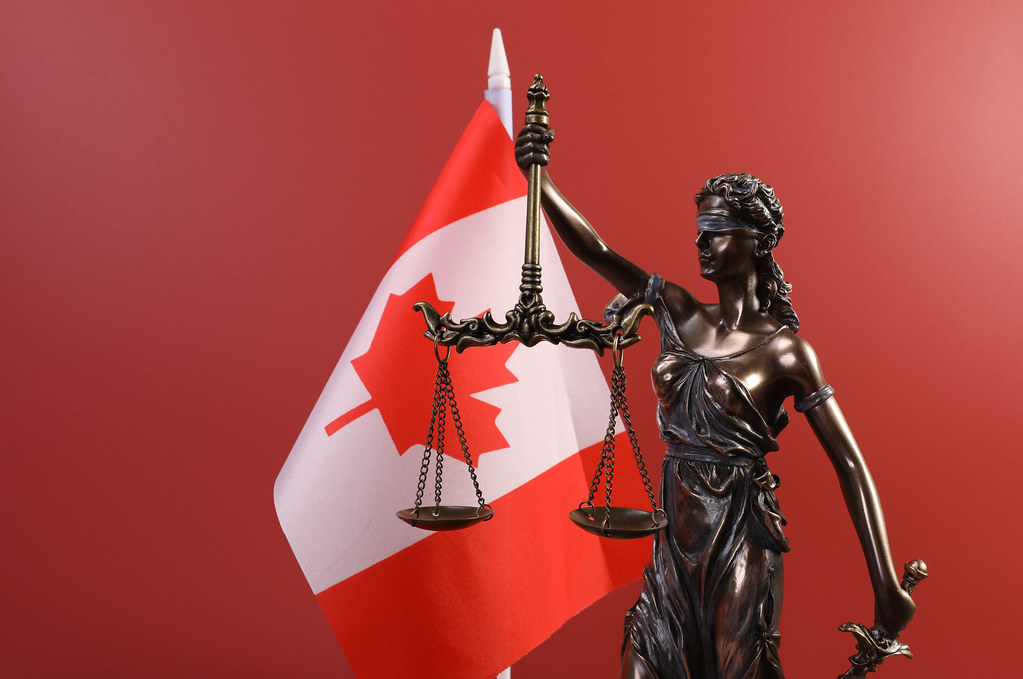 Statue of Lady Justice and flag of Canada on red background