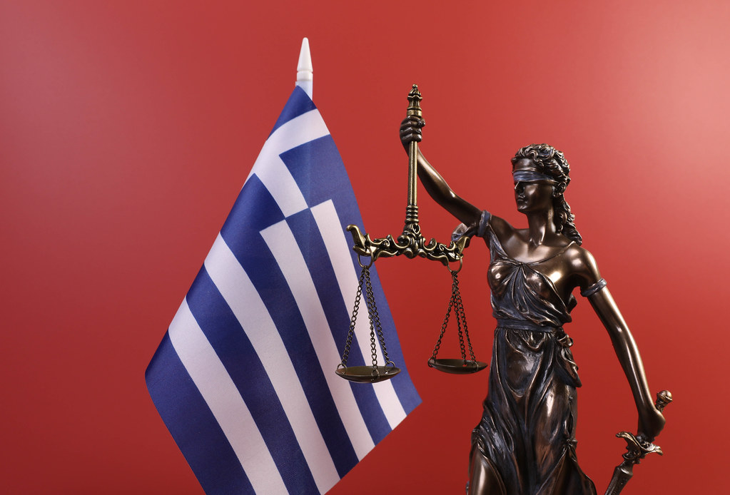 Statue of Lady Justice and flag of Greece on red background