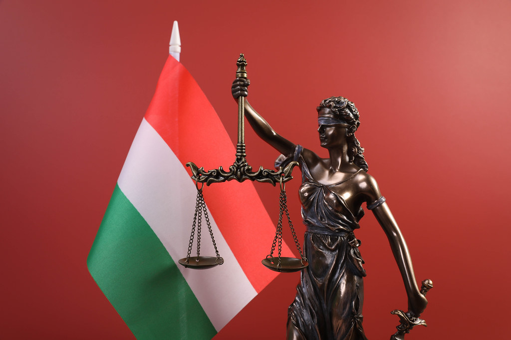 Statue of Lady Justice and flag of Hungary on red background