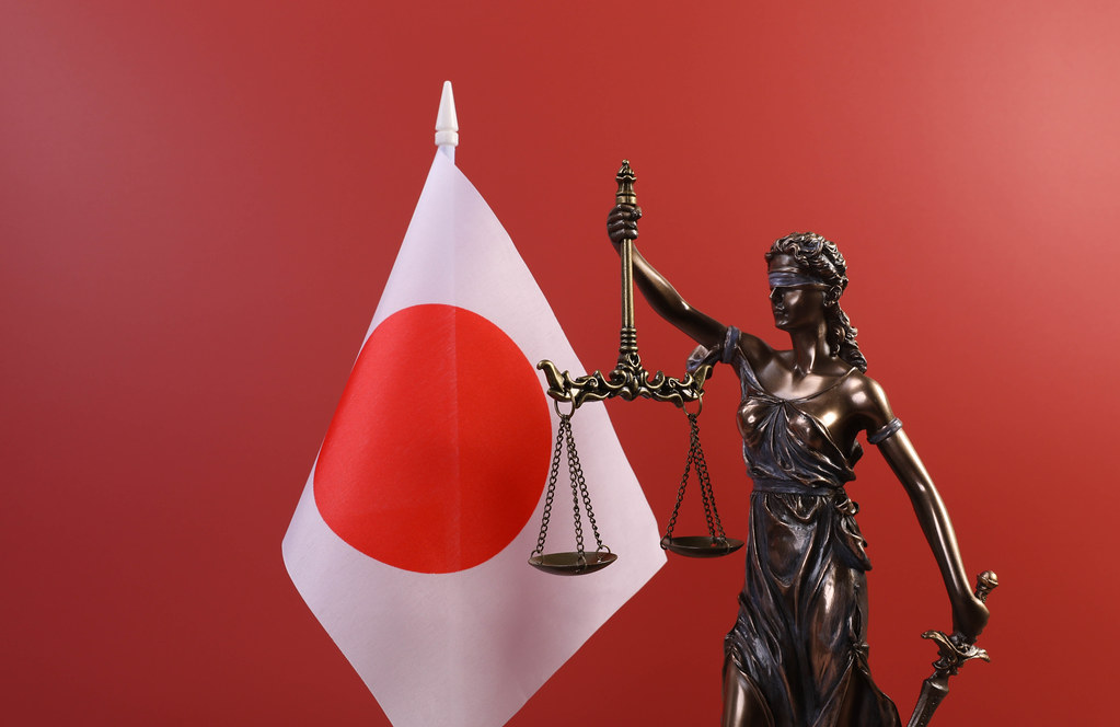 Statue of Lady Justice and flag of Japan on red background