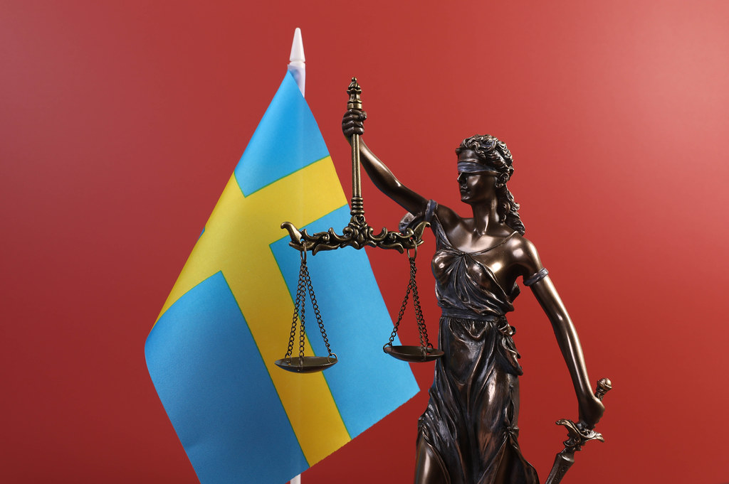 Statue of Lady Justice and flag of Sweden on red background