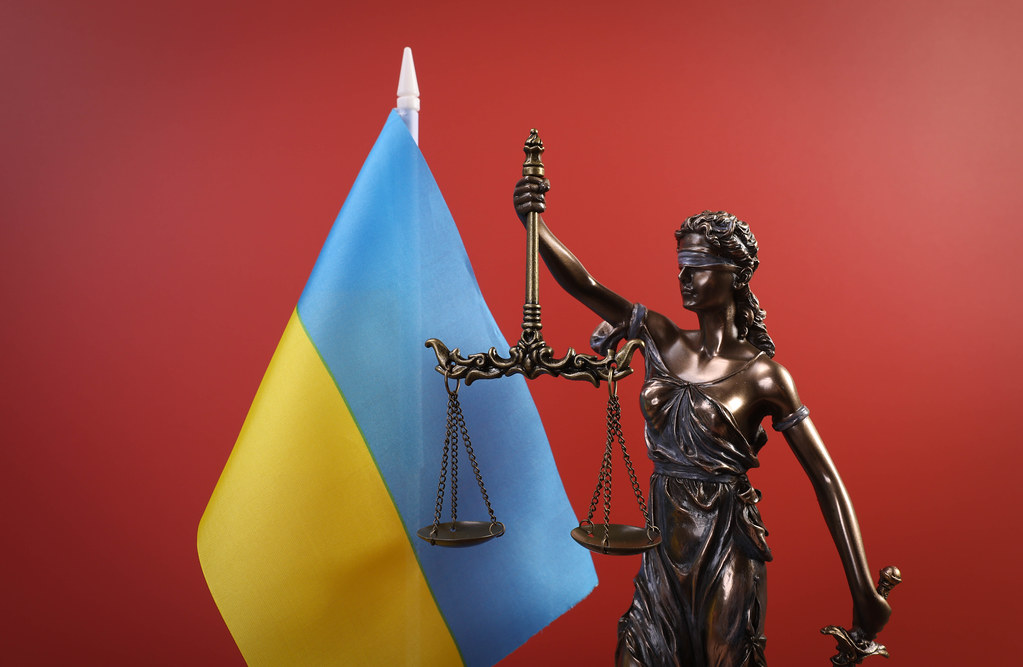 Statue of Lady Justice and flag of Ukraine on red background