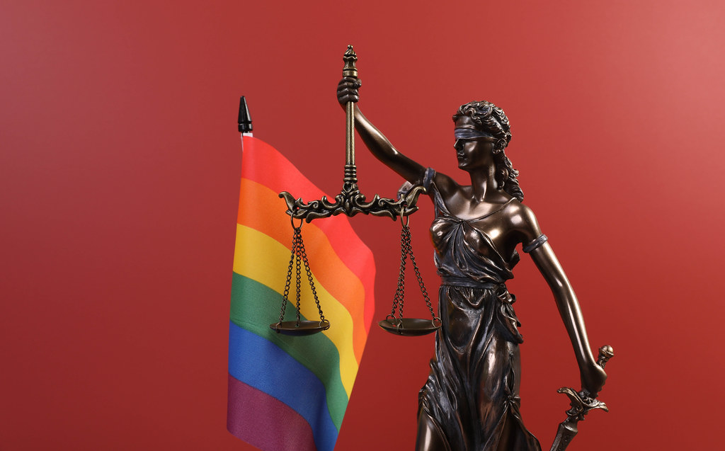 Statue of Lady Justice and rainbow flag on red background