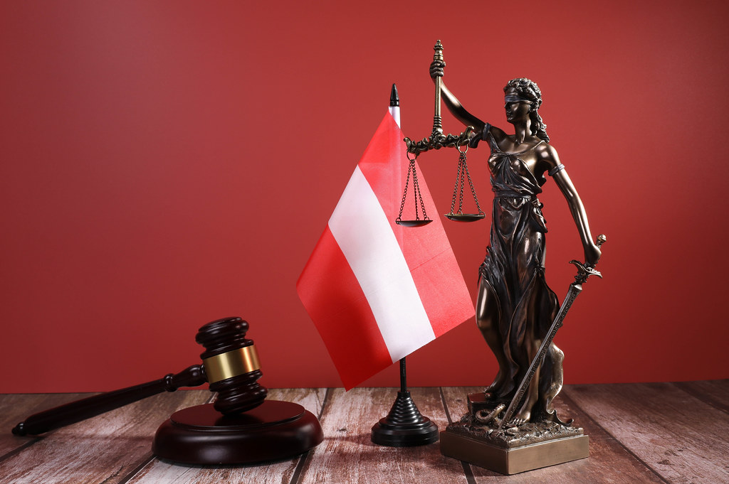 Statue of Lady Justice with Judge gavel and flag of Austria