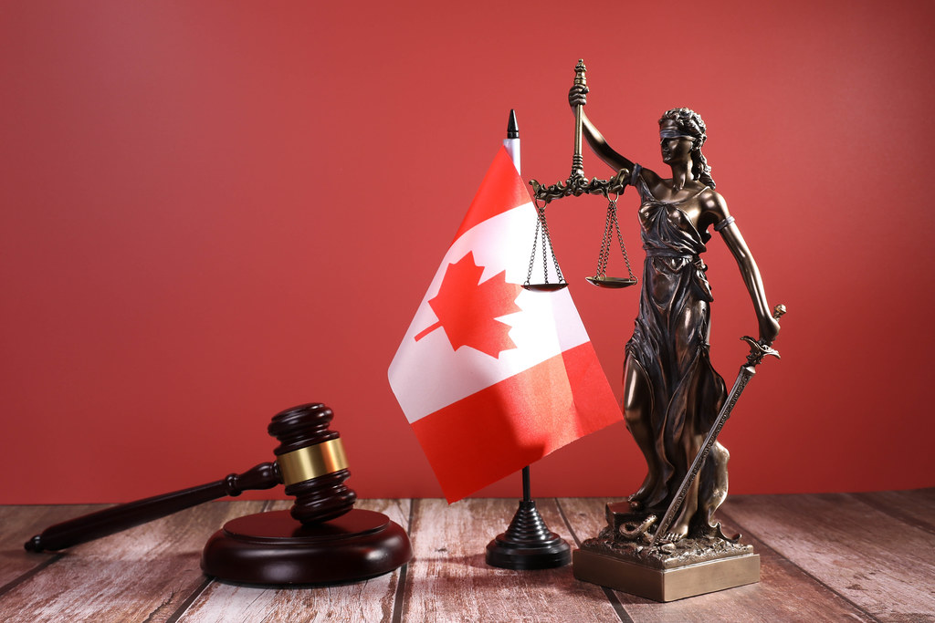 Statue of Lady Justice with Judge gavel and flag of Canada