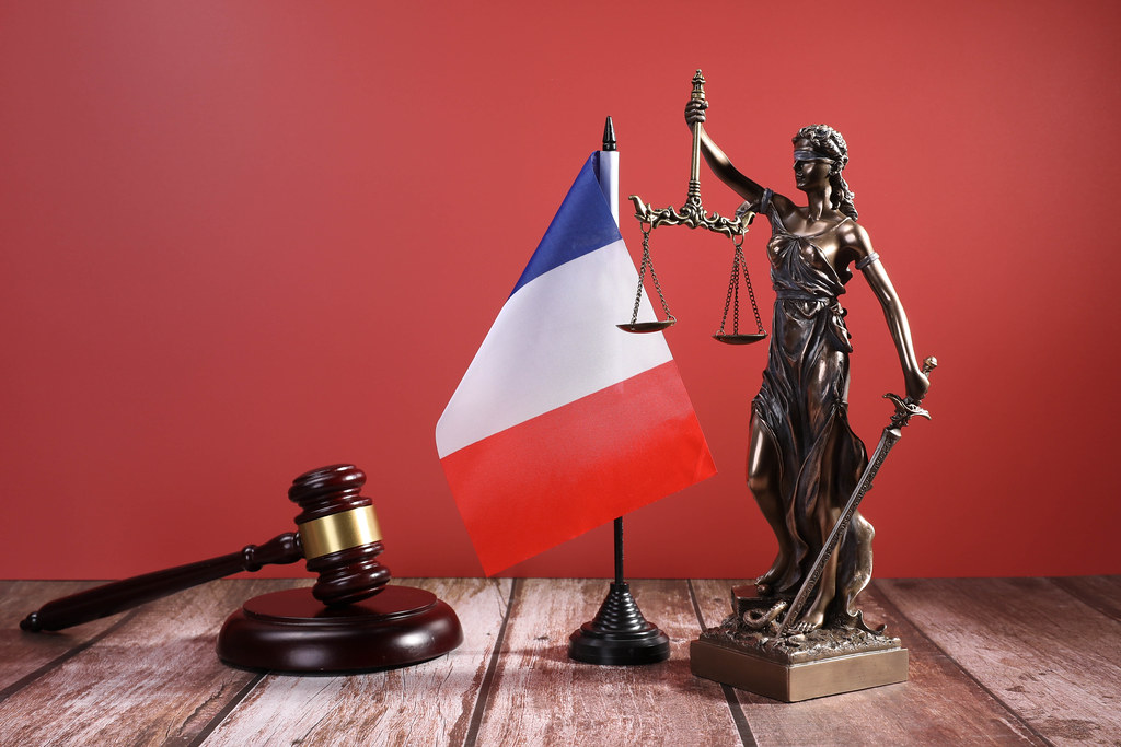 Statue of Lady Justice with Judge gavel and flag of France