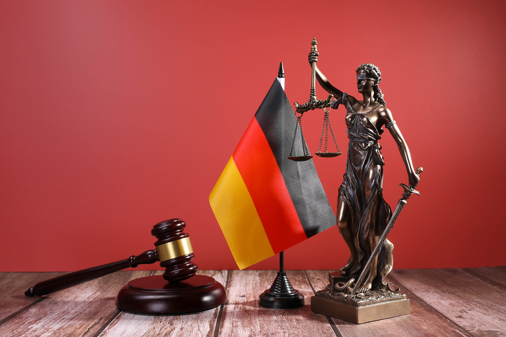 Statue of Lady Justice with Judge gavel and flag of Germany