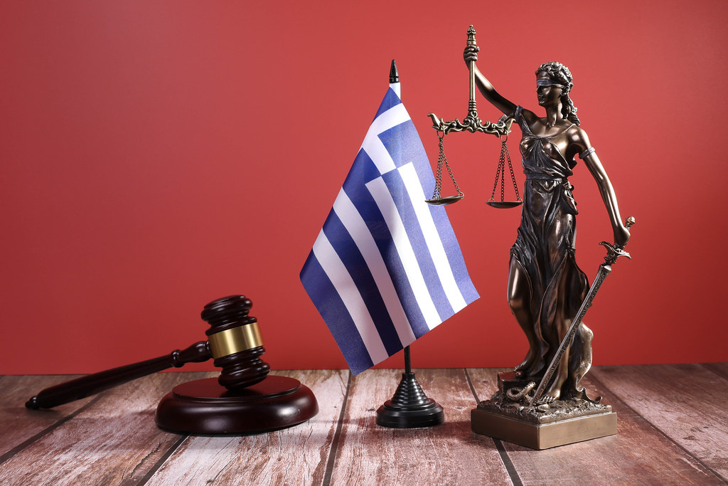 Statue of Lady Justice with Judge gavel and flag of Greece