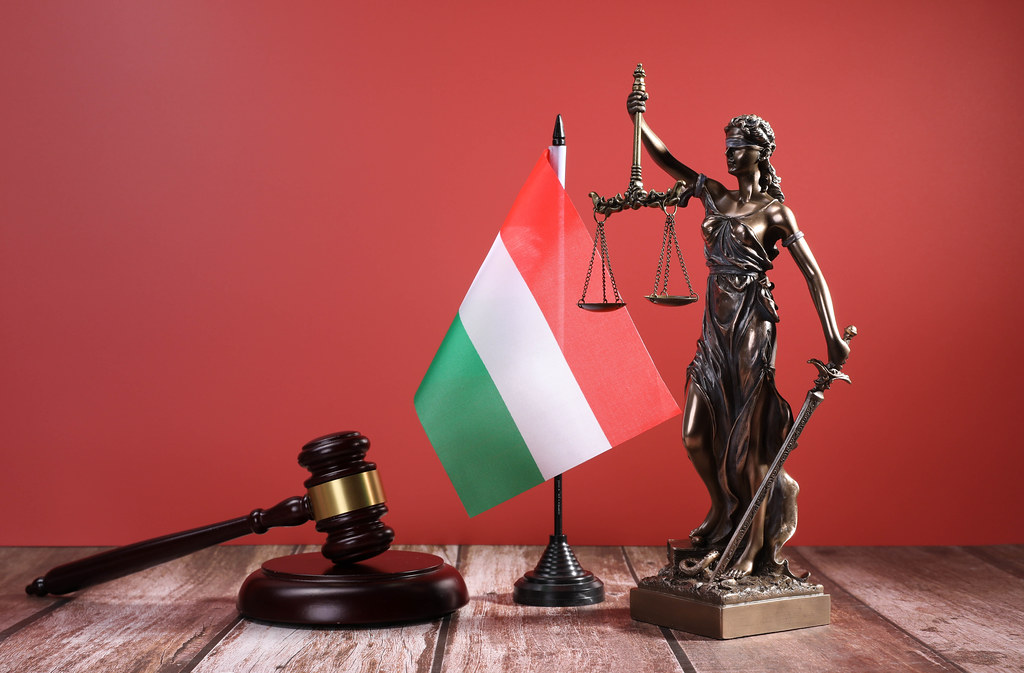 Statue of Lady Justice with Judge gavel and flag of Hungary