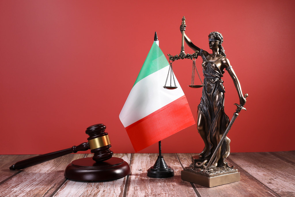 Statue of Lady Justice with Judge gavel and flag of Italy