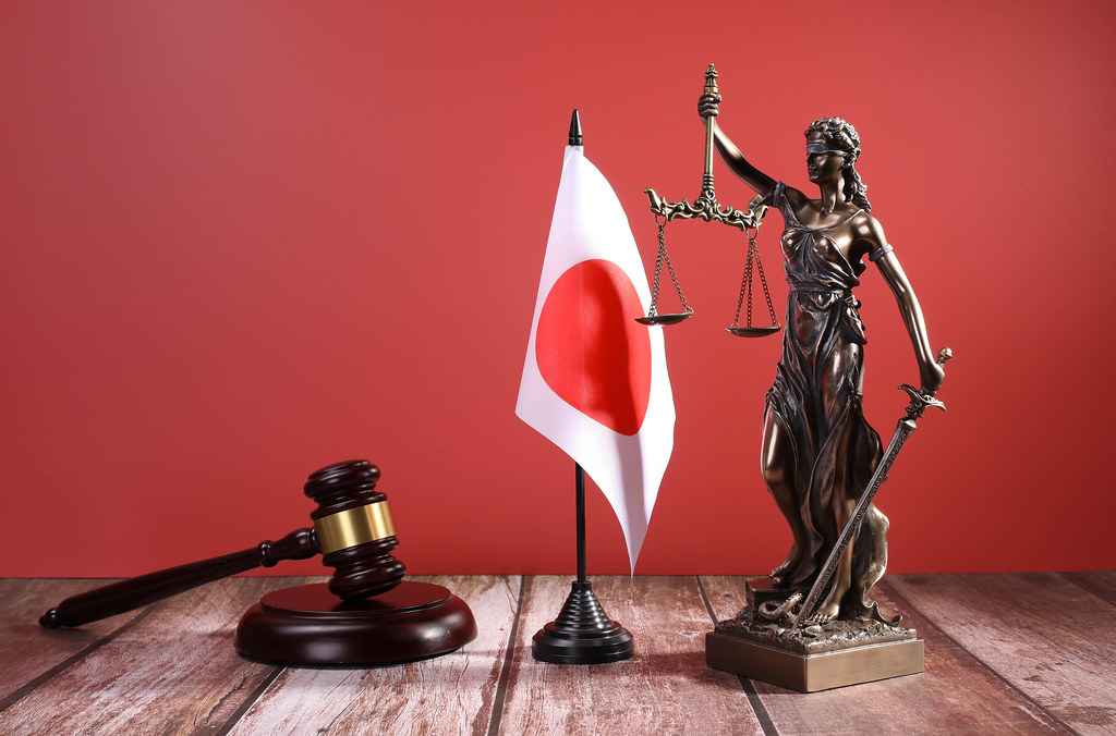 Statue of Lady Justice with Judge gavel and flag of Japan