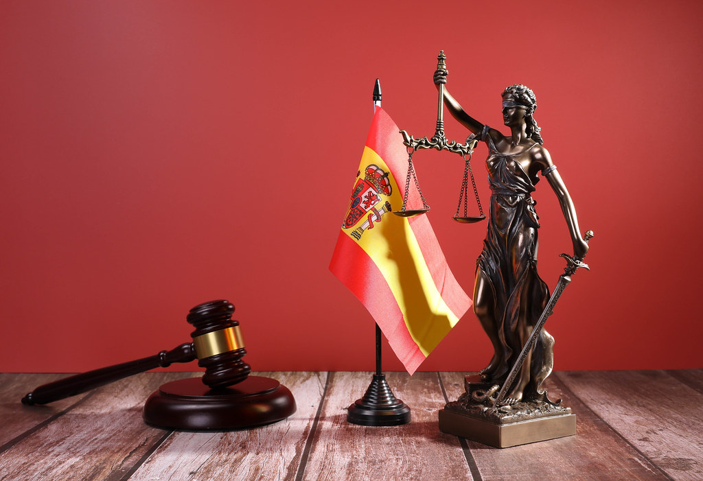 Statue of Lady Justice with Judge gavel and flag of Spain