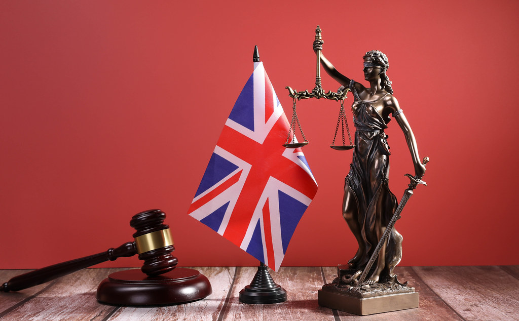 Statue of Lady Justice with Judge gavel and flag of United Kingdom